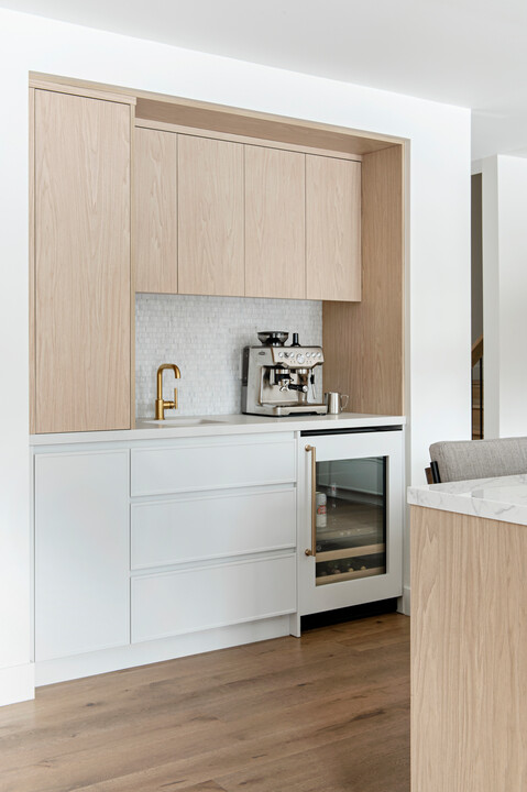 A coffee bar with light wood cabinets and wood floors.